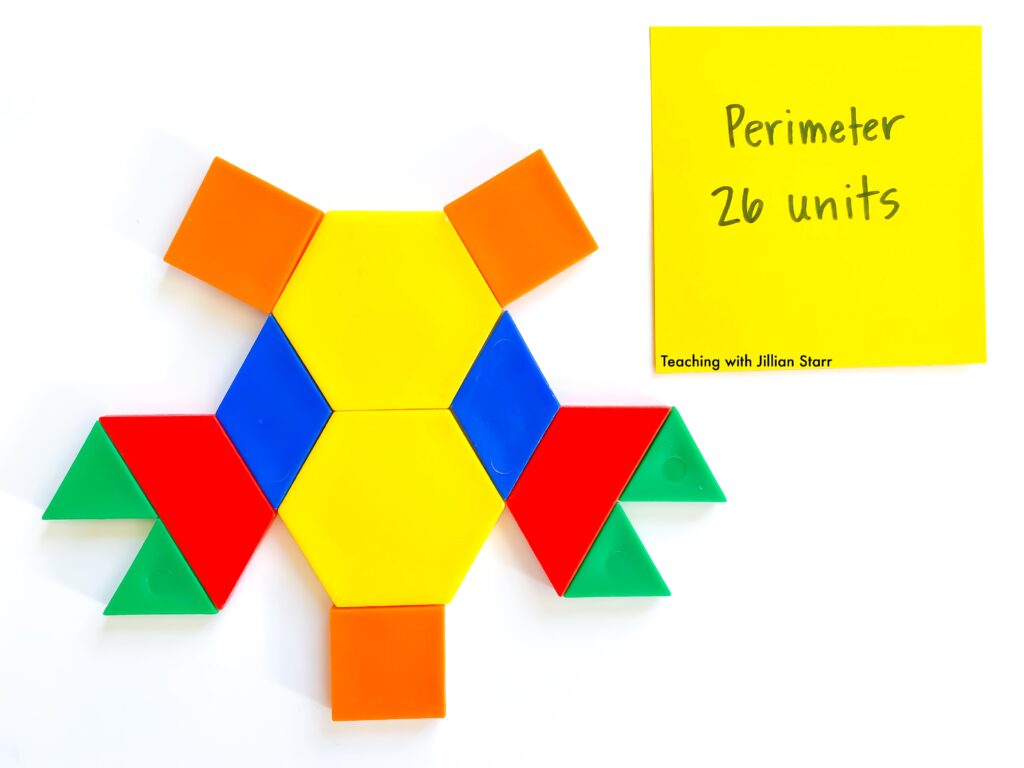 A variety of pattern blocks are arranged. There is a post-it note that marks the perimeter of the arrangement. Pattern blocks are a manipulative that make an excellent extension into perimeter.