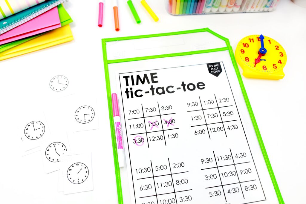 telling time to the half hour tic-tac-toe, with four boards showing digital clocks showing times to the half hour. Cards with analog clocks to the half hour are scattered next to it.

