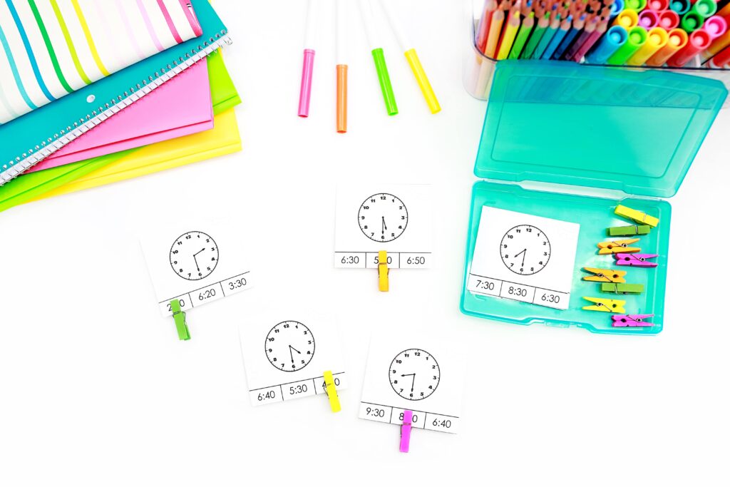 clip cards to review telling time to the half hour. Each card shows a clock face with a time to the half hour, and three possible digital clock options below. Students clip the card on the digital clock they think is a match.