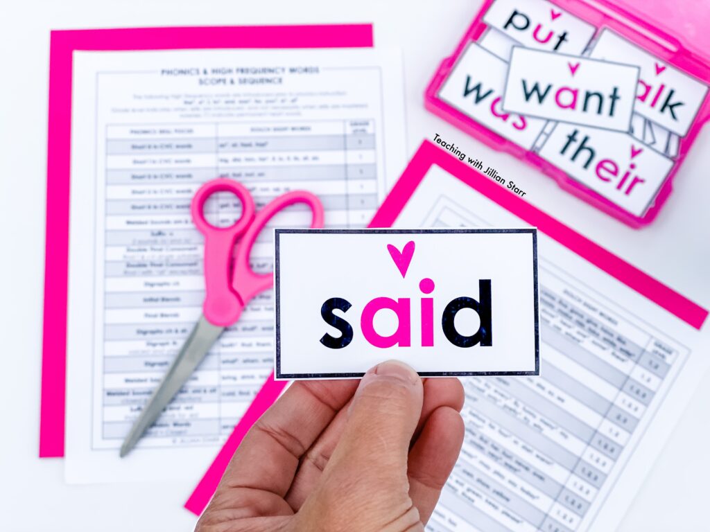 A close up of the heart word card "said", with a pile of heart word cards in an iris photo container, as well as the free phonics scope and sequence in the background.